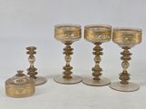 four gold colored glass goblets and a box on a white surface
