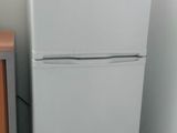 a microwave on top of a refrigerator in a small room