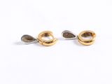 a pair of gold and silver earrings sitting on top of a white surface