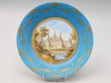 une assiette bleue sur laquelle est représenté un château