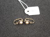 a pair of earrings with pearls and a price tag on a table