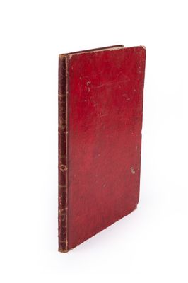 un vieux livre rouge posé sur une surface blanche