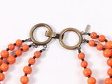 an image of a close up of a necklace with orange beads
