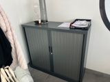 a small cabinet with a mirror and a bag on it