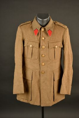 un uniforme marron posé sur un présentoir à mannequin, sur fond noir
