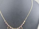 a necklace with purple stones and gold chains on a mannequin