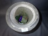 a stone vase with a purple flower inside of it