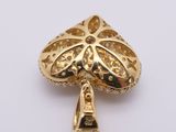 a close up of a gold plated pendant on a white surface