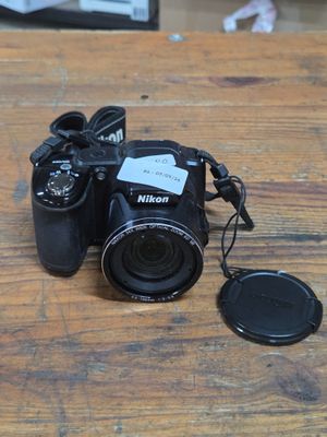 a black camera sitting on a wooden table next to a camera cap