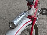 a close up of a red and white bicycle parked on the street