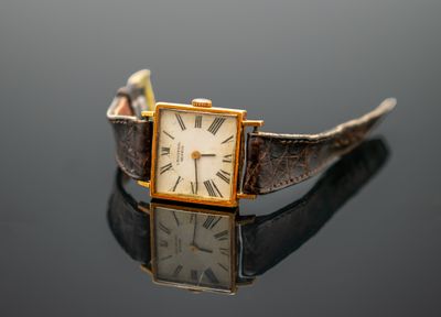 un gros plan d'une montre-bracelet posée sur une surface réfléchissante