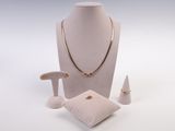 un mannequin blanc portant un collier, une bague et des boucles d'oreilles