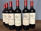 six bottles of red wine are lined up on a wooden table