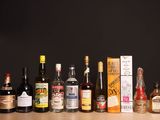 des bouteilles d'alcool alignées sur une table devant un fond noir