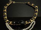 a necklace with pearls and gold chains on a black table
