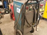 une photo d'une soudeuse dans un garage, à côté d'autres équipements