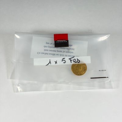 une pièce d'or dans un sachet transparent sur lequel figurent des caractères chinois