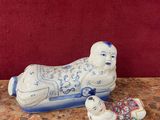 une figurine en porcelaine représentant un chien endormi et un livre posé sur une table