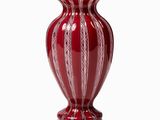 un vase rouge posé sur une surface blanche