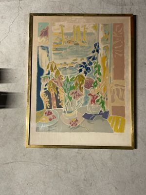 un tableau accroché au mur à côté d'un vase de fleurs