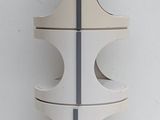 a tall white vase with four holes on the side of it