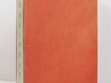 a red book sitting on top of a table next to a white wall