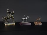 three silver figurines of a man on a horse and a man on a horse