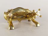 une figurine en or représentant une vache posée sur une table blanche