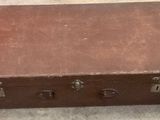 a brown suitcase sitting on the floor next to a piece of paper