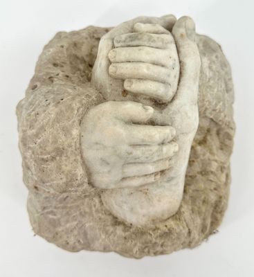 a statue of two hands holding each other on a rock