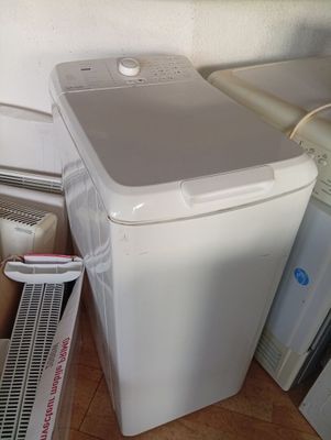 a white washing machine sitting on the floor next to a stack of boxes