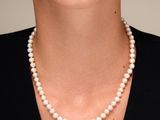 une femme portant un collier de perles et une robe noire