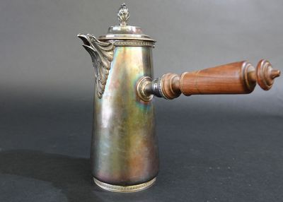une cafetière en argent avec un manche en bois sur une table