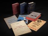 Plusieurs livres sont disposés sur une surface noire, sur fond noir.