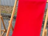 a red beach chair that is sitting in the gravel