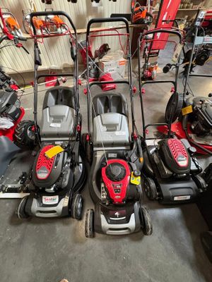 Plusieurs tondeuses à gazon sont alignées dans un garage