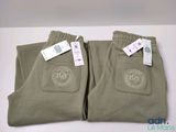 two pairs of men ' s pants with tags on them sitting on a table