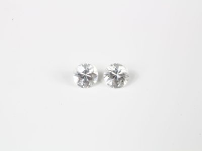 une paire de boucles d'oreilles à clous ornées de diamants blancs posées sur une surface blanche
