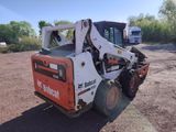 a picture of a small ski - loader parked in a dirt lot