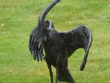 une statue représentant un oiseau, posée dans l'herbe