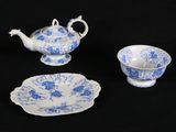three pieces of blue and white china on a black surface