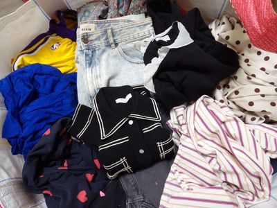 a suitcase full of clothes and clothes sitting on a bed