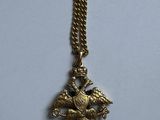 a close up of a gold necklace with a bird on it