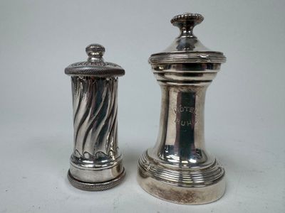 deux salières et poivrières en argent posées sur une surface blanche