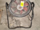 a fan that is sitting on the ground in a garage