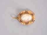 an image of a gold broochle with a shell in the center