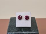 a pair of red ruby stone stud earrings sitting on top of a marble block