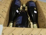trois bouteilles de vin dans un carton sur une table