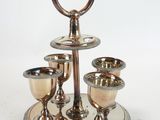 a silver plate with three cups on it on a stand