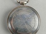une petite montre de poche en argent ornée d'une croix
